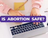 Young woman typing on a laptop with text overlay asking 'Is Abortion Safe?'