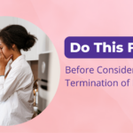 Concerned young woman with hands covering face, standing in a kitchen, representing emotional decision-making before considering termination of pregnancy.