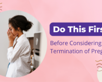 Concerned young woman with hands covering face, standing in a kitchen, representing emotional decision-making before considering termination of pregnancy.