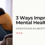 A woman in a yellow sweater sits on a couch with her head resting on her arms, appearing reflective and emotional. The text reads, "3 Ways to Improve Mental Health When Facing an Abortion Decision.